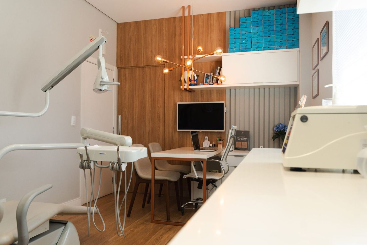Consultório da OrtoHaus com cadeira odontológica, mesa de planejamento digital e lustre de cobre